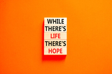 Life and hope symbol. Concept word While there is life there is hope on wooden block. Beautiful orange table orange background. Business lifestyle life and hope concept. Copy space.
