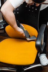 Housekeeper is extracting dirt from yellow armchair using dry cleaning extraction machine. Cleaner is cleaning chair with washing vacuum cleaner extractor machine for dry clean upholstered furniture.