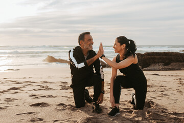 Positive mature european couple tying shoelaces, give high five, go for run, enjoy workout together in morning