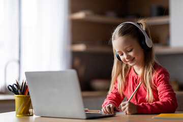 Distant Education. Little Girl In Headphones Study With Laptop And Taking Notes