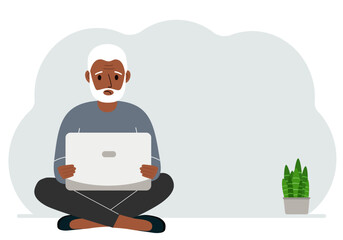 A man sits cross-legged in his hands holding a laptop. The concept of work, education, reading, watching videos.