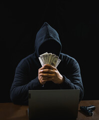 Hacker spy man wearing a black shirt, sitting on a chair and a table, is a thief, hands holding...