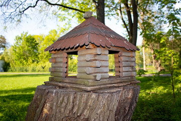 Wooden feeder for wild animals living in the grove. A manger for for squirrels and other rodents made in a form of a house in the park.