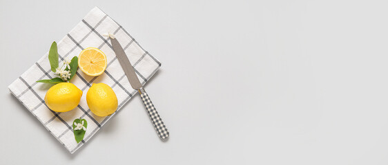 Napkin with knife and fresh yellow lemons on light background with space for text