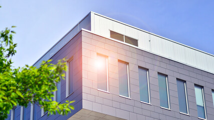Eco architecture. Details of facade glass and aluminum panels on  building. Green tree and modern office building. The harmony of nature and modernity. 