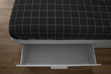 Modern bed with open drawer in room