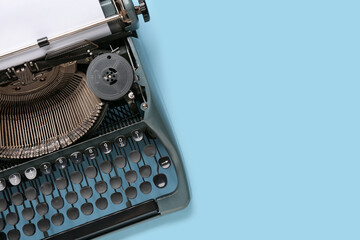 Vintage typewriter with blank paper sheet on blue background