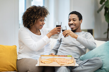 Cheerfy black lovers have dinner at home, eating pizza