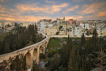 Gravina in Puglia, Bari, Italy: landscape at sunrise of the old town and the ancient aqueduct bridge (viaduct Madonna della Stella) over the deep ravine