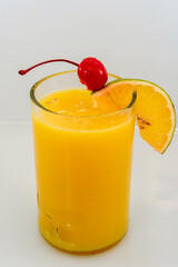 vaso de jugo de naranja y decorado con una rodaja de naranja y cereza