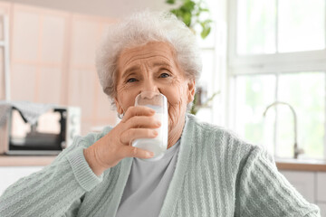 Senior woman drinking milk in kitchen, closeup