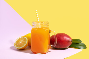 Mason jar of fresh mango smoothie and lemon on color background