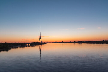 Silhouette of Riga panorama with television tower reflecting in Daugava river after the sunset on summer evening