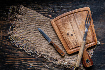 Wooden Cutting board, knife and burlap. Table dark background. top view. copyspace.