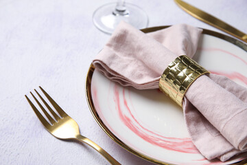 Plate with folded napkin, gold cutlery and glass on grunge white background