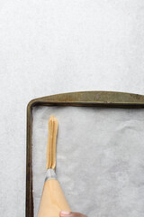 Churros dough piped on a parchment lined baking sheet, choux pastry dough about to be fried, process of making churros