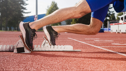 Male sprinter feet, in black sneakers, pushing off from the starting block, and start a race, close up shot.