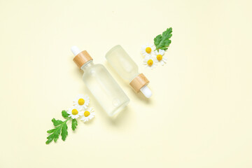 Fototapeta na wymiar Composition with bottles of essential oil, chamomile flowers and leaves on color background