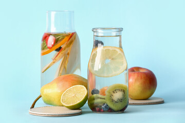 Bottles of infused water with different sliced fruits on blue background