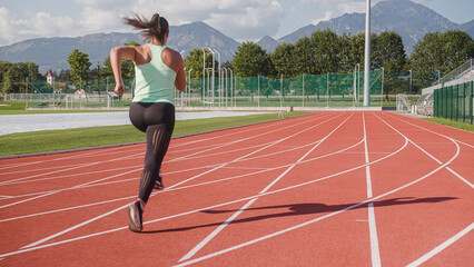 Athlete woman starting to run on the athletic track from the three-point sprint start position