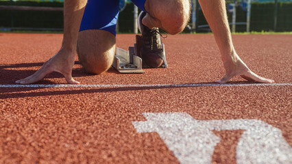 Caucasian male arms and hands on the running track starting line, ready, set and go sprint position