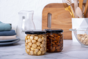 Glass jars with honey and nuts. Almonds and hazelnuts in honey in kitchen interior