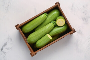 Wooden box with fresh green zucchini on white background