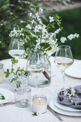 Rustic zero waste wedding decor with natural elements. Fresh spring blooming flowers, candles, linen napkins, wine glasses. Eco friendly decoration for the special holiday dinner. Romantic cozy place