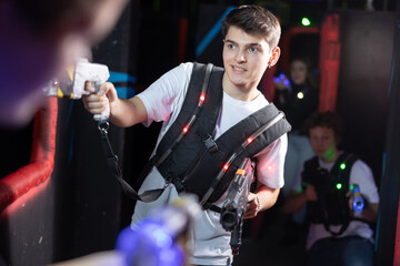 Excited teenager having fun playing lasertag in arena