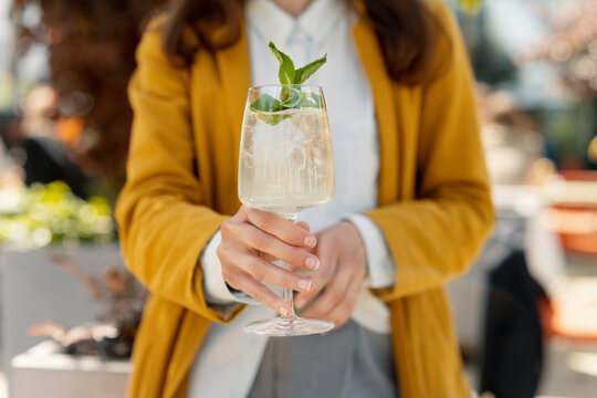 Woman holding iced summer spritz cocktail in the city