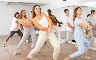 Happy multiracial men women of different ages performing dynamic energetic dancing movements in modern loft studio