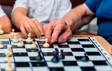 Naklejka premium Grandfather with his grandson playing chess and board games. Concept of mental sport and family union. Generated with AI