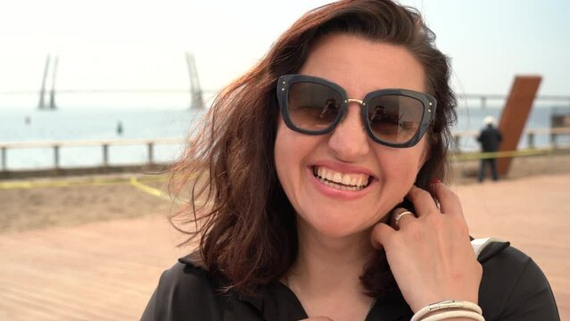 A young woman in sunglasses is smiling and happy