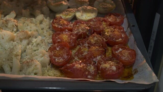 hot tomatoes and vegetables fresh from the oven, still cooking from the heat of the oven

