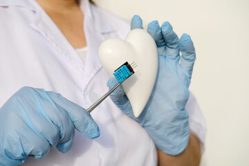 female scientist, doctor holding heart model, microprocessor, microchip, biochip tweezers for...