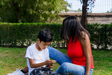 Happy mother and son using mobile phone together in a park.