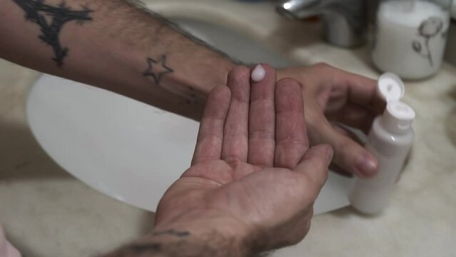 person with tattoos takes care of tattooed skin with special cream
