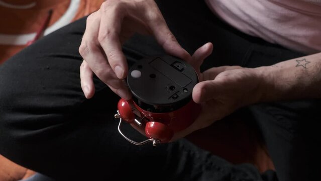 man's hands disassembling an alarm clock with a screwdriver and checks that it works
