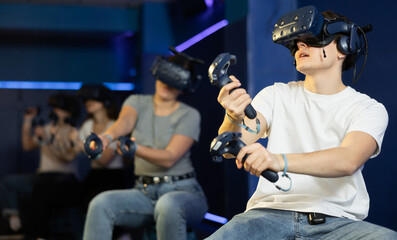 Emotional joyful boy and girl in virtual glasses plays a game by controlling joysticks