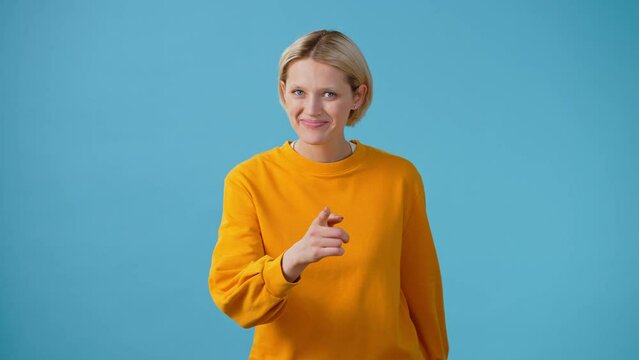 Smiling woman points finger and makes heart shape with hands