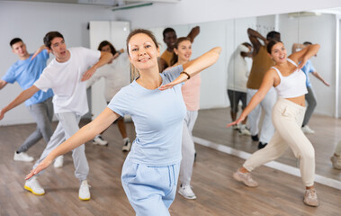 Group of sporty young adult multinational sports people making straight line with hands exercising dancing in gym
