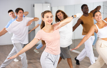 Group of sporty young adult multinational sports people making straight line with hands exercising...