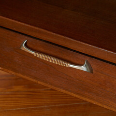 Mid-century modern sculpted metal drawer pull. Vintage walnut furniture. Close-up detail of the...