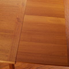 Mid-century modern teak draw leaf table. Close-up detail photographed from above highlighting the table leaf with a wood grain texture.