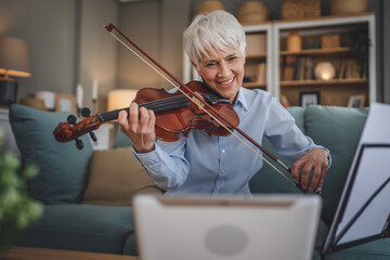 Mature senior caucasian woman learn to play violin practice at home - obrazy, fototapety, plakaty