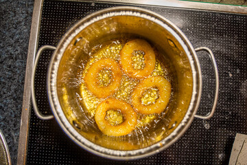 Fried golden calamari rings in a pot filled with boiling oil on the hotplate