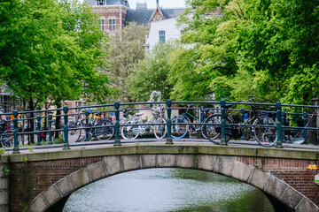bridge in Amsterdam with bicycles and green trees