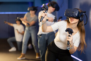 girl in virtual reality helmet crouches down and dodges flying asteroids during space adventure...