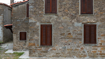 Fototapeta na wymiar Facade of a stone house with brown shutters. Gokceada, Imbros island Canakkale, Turkey