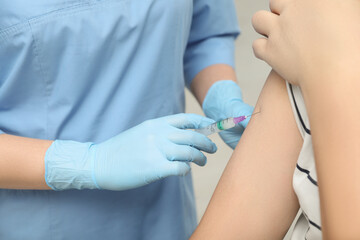 Doctor giving hepatitis vaccine to patient on grey background, closeup